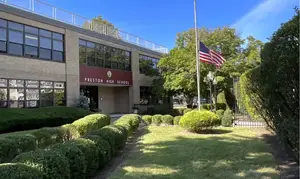 Preston High School entrance in the Bronx with American flag at half-mast, saved by Bally’s $8.5 million deal to prevent closure