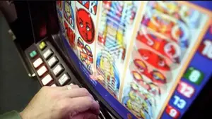 Player using a UK slot machine with colorful reels and illuminated control buttons in an adult gaming center.